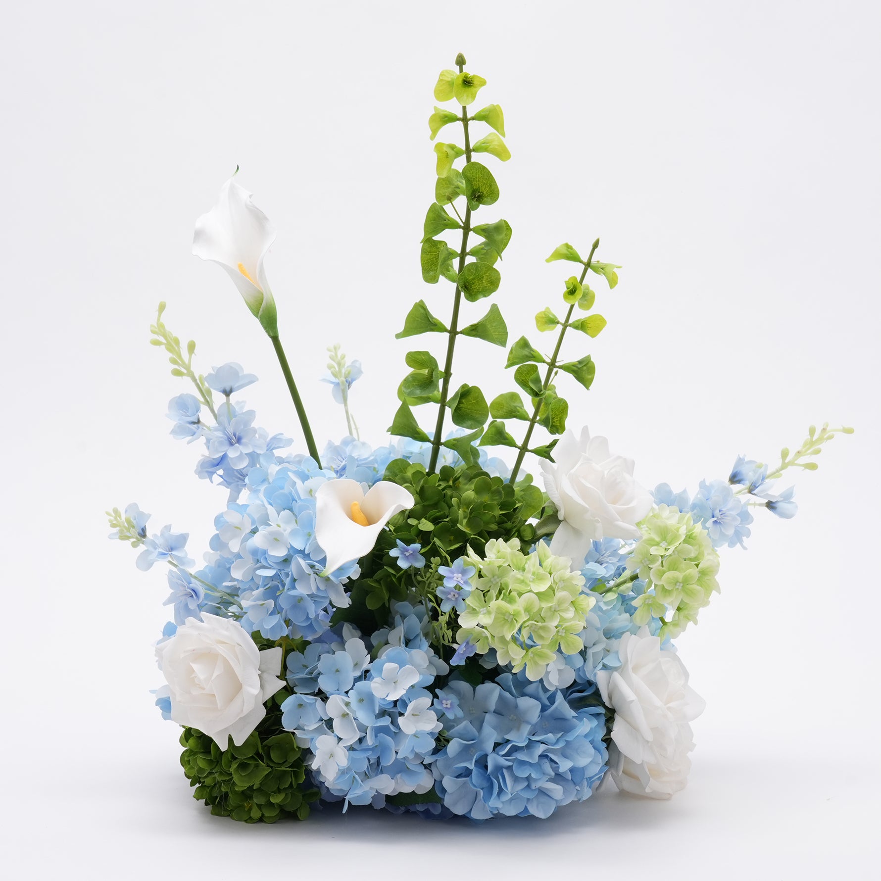 Close‑up indoor shot of mixed silk hydrangea, rose and calla lily table centerpiece
