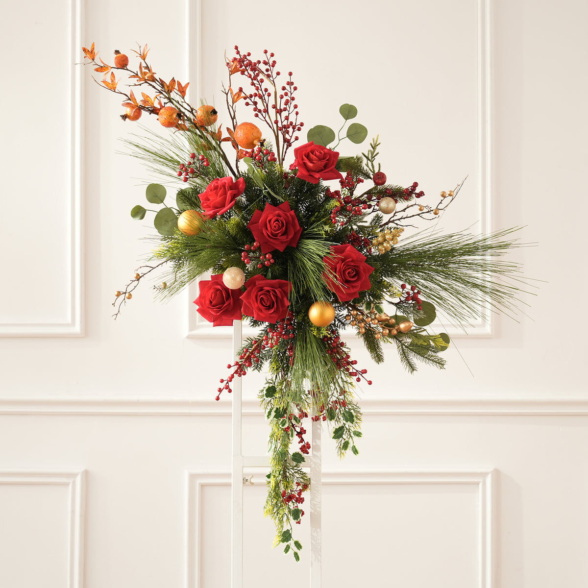 Elegant christmas table centerpiece florals with red roses, mixed evergreen and golden baubles