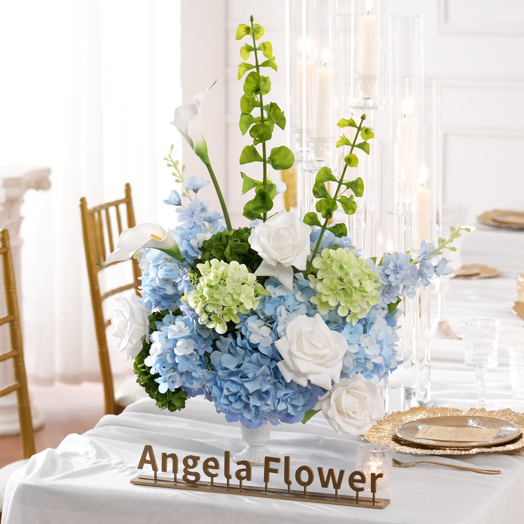 Long wedding dinner table decorated with soft blue‑white faux floral vase arrangements