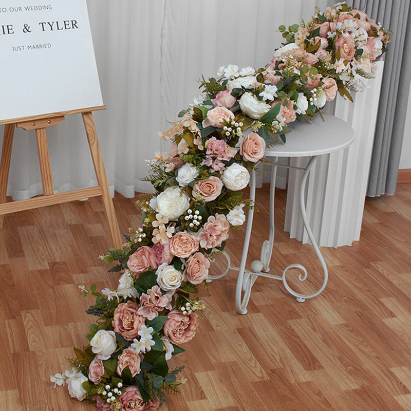 Close up detail shot of artificial peony, rose and filler flowers on long trailing wedding floral table runner