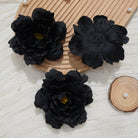 Black silk rose heads on linen fabric background