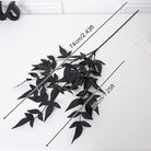 Single stem black artificial foliage branch studio shot