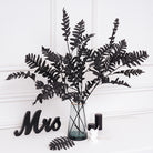 Bunch of black faux foliage stems in clear vase