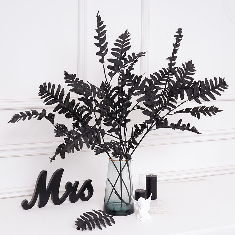 Bunch of black faux foliage stems in clear vase