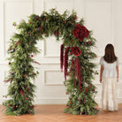 Faux red christmas baubles mixed with frosted pine branches holiday floral closeup