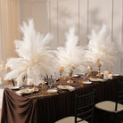 Ivory ostrich feather centerpiece on dark brown linen covered dining table