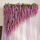 Outdoor garden wedding scene with wisteria backdrop and flower lined aisle