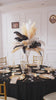 Ostrich feather arrangement displayed in vintage glossy gold candlestick vase