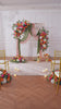 Garden wedding arch styled with sunset artificial flowers and drape
