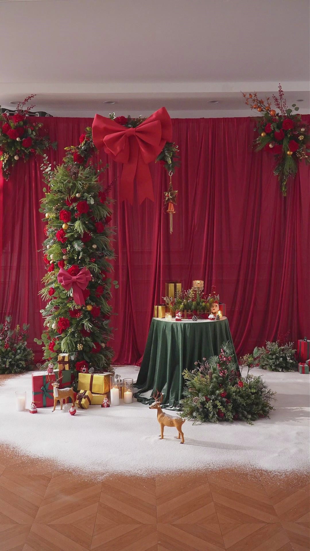 Outdoor holiday display of red rose floral hoop arch with gift boxes and candle decor on lawn