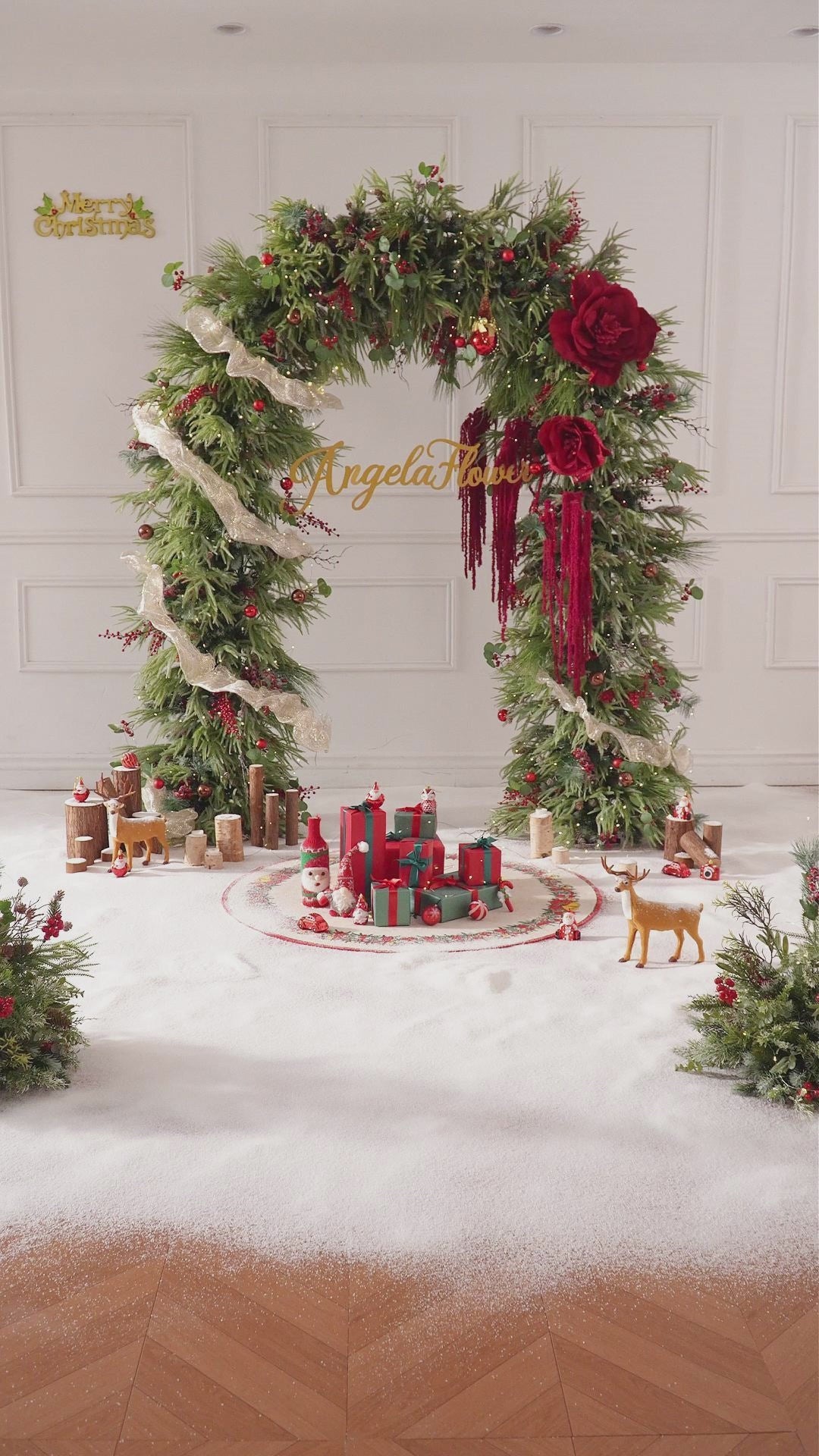 Outdoor holiday arch installation with faux winter greenery and deep red magnolia blooms