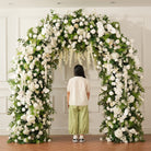 White flower petals scattered on floor under wedding flower arch