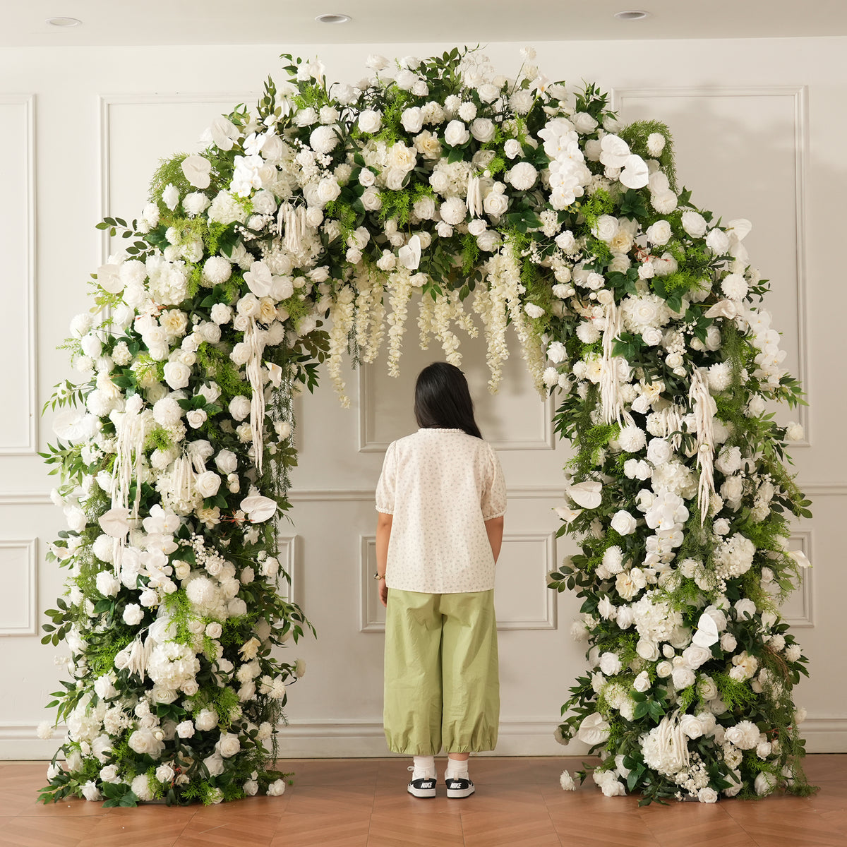 White flower petals scattered on floor under wedding flower arch