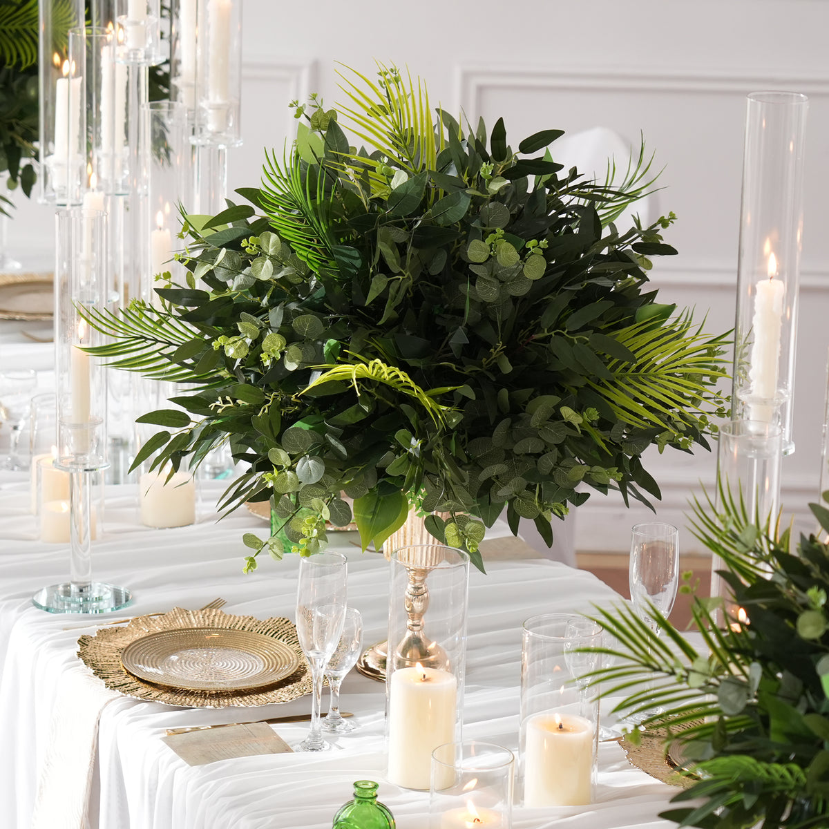 Faux palm frond and round eucalyptus table arrangement for tropical themed events