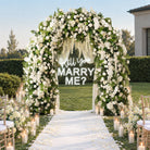 White floral arch for beach sunset wedding ceremony